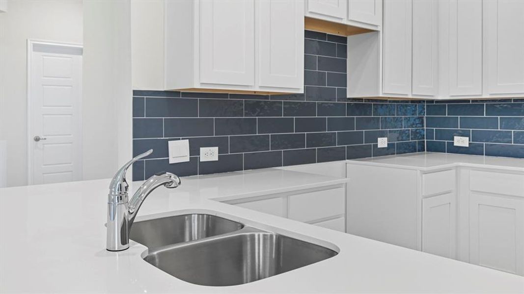 Kitchen featuring white cabinets, backsplash, and light stone countertops Kitchen featuring white cabinets, backsplash, and light stone countertops