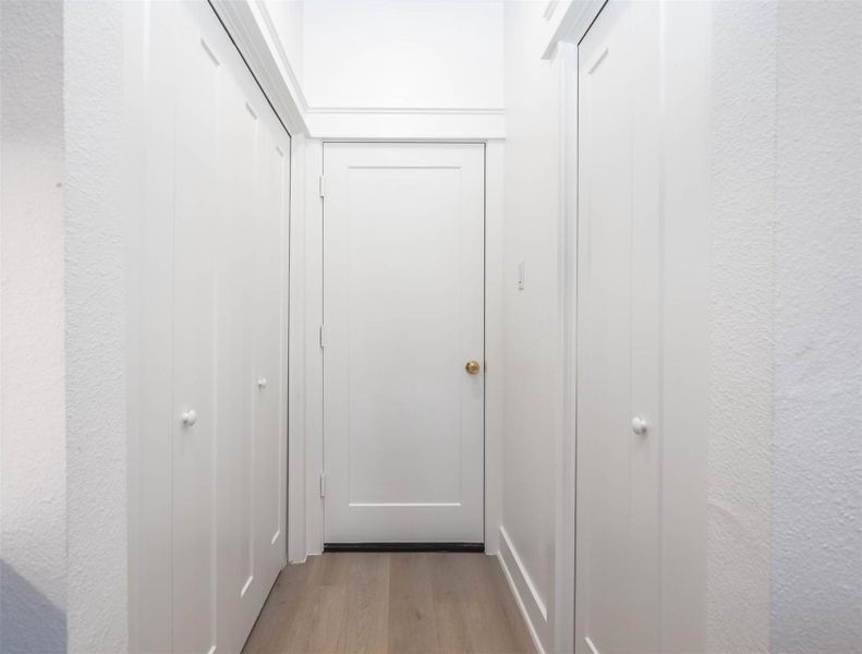 Hallway leading to the garage with pantry on the left and utility room on the right.