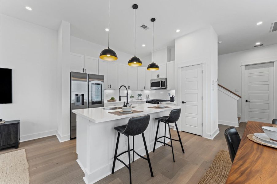 This centrally positioned kitchen island serves as a stylish anchor within the open-concept layout, offering clear sightlines to the dining area, living space, and the front yard. Its placement encourages seamless interaction, whether prepping meals or entertaining guests, while natural light pours in through the nearby windows. The island’s sleek design and functional surface make it a hub of activity, framed by elegant finishes tying together comfort and sophistication.