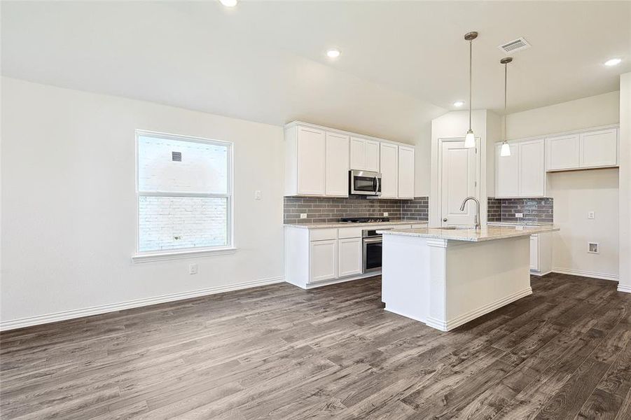 Kitchen featuring a kitchen island with sink, white cabinetry, stainless steel appliances, sink, and dark hardwood / wood-style floors