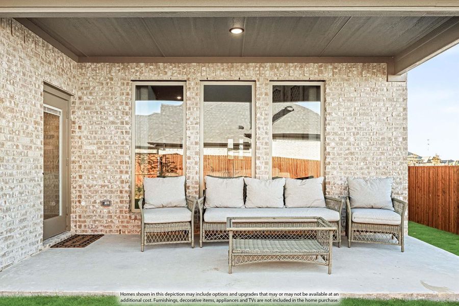 Covered back patio with wicker seating set against a light brick exterior wall and wood ceiling