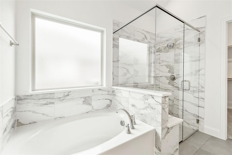 Master bathroom with soaking tub, glass walk-in shower, and marble tile walls Master bathroom with soaking tub, glass walk-in shower, and marble tile walls