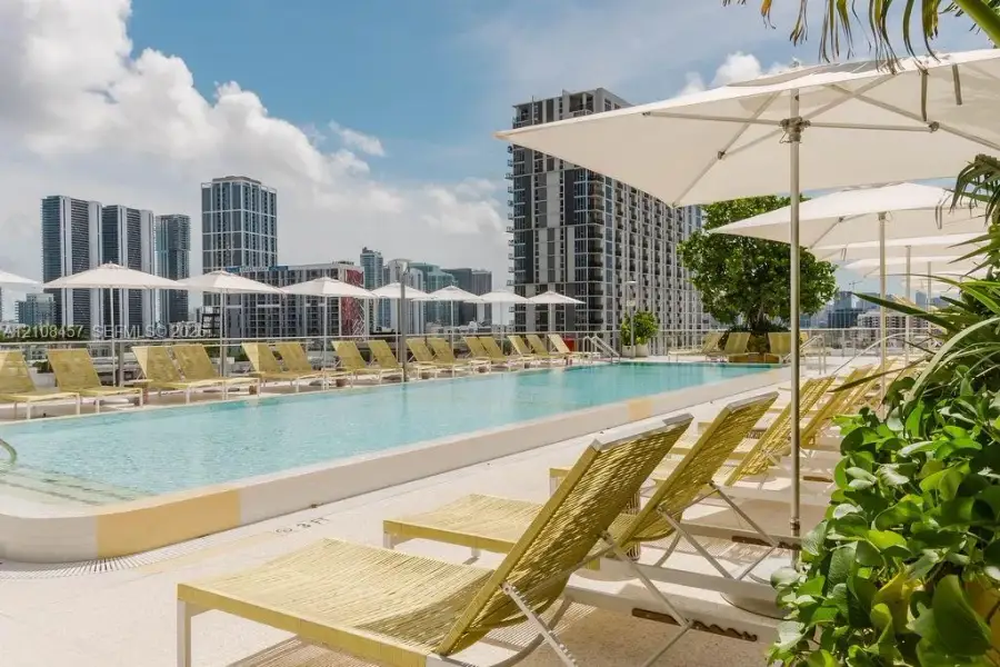 Rooftop swimming pool with a light-colored paved deck, surrounding metal railing, and integrated pool steps Rooftop swimming pool with a light-colored paved deck, surrounding metal railing, and integrated pool steps