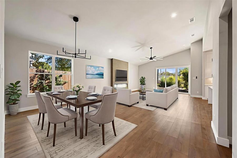 Dining room with light wood finished floors, recessed lighting, vaulted ceiling, a chandelier, and a ceiling fan Dining room with light wood finished floors, recessed lighting, vaulted ceiling, a chandelier, and a ceiling fan
