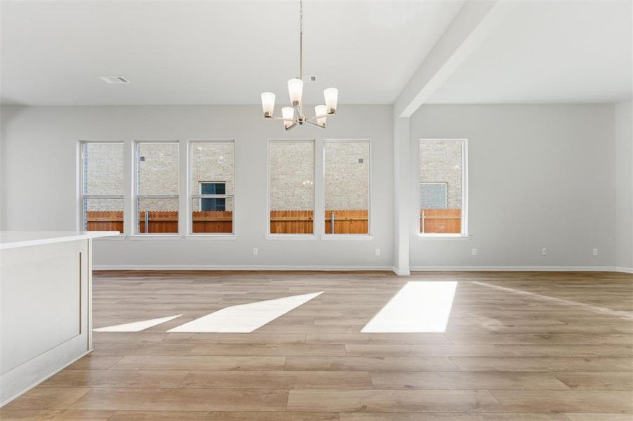 Unfurnished room featuring light wood-style floors, a chandelier, and beam ceiling