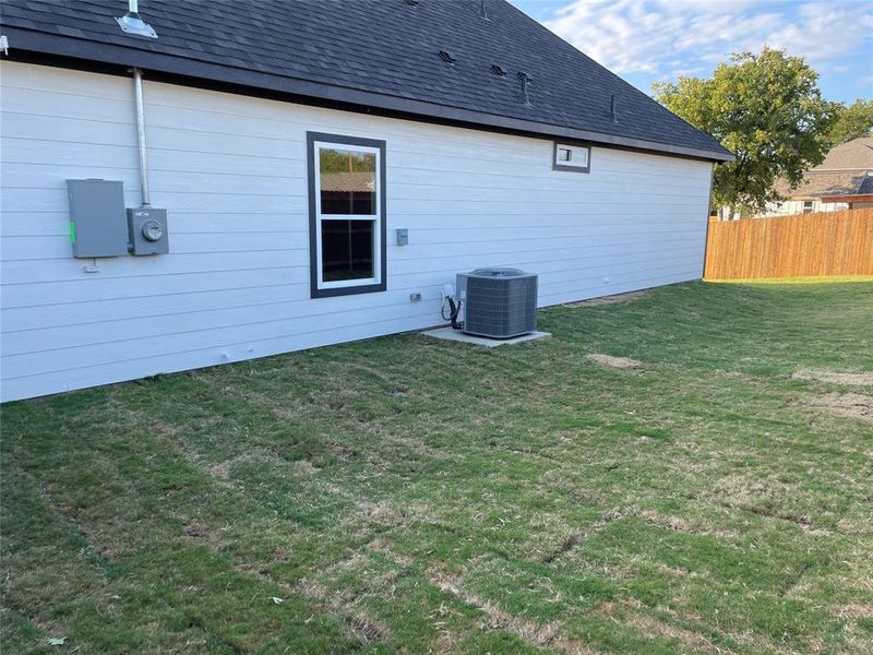 Rear view of house with central air condition unit and a yard