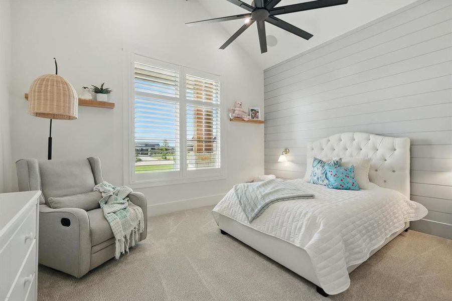 Bedroom featuring light carpet, a ceiling fan, wood walls, and high vaulted ceiling Bedroom featuring light carpet, a ceiling fan, wood walls, and high vaulted ceiling
