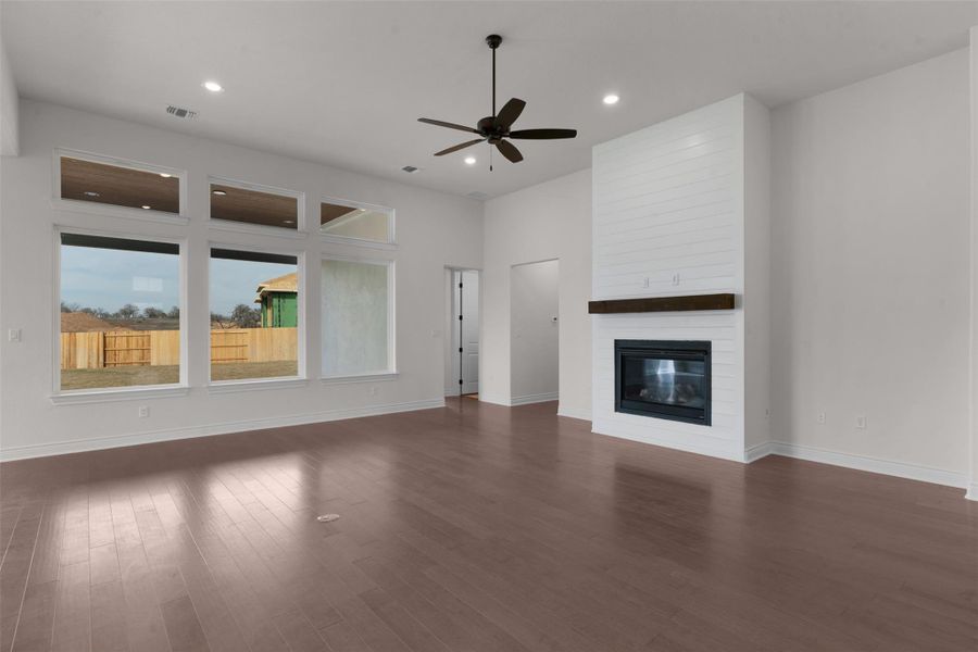 Unfurnished living room featuring a ceiling fan, a large fireplace, dark wood-style flooring, and recessed lighting