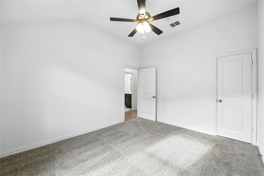 Unfurnished bedroom featuring carpet floors, vaulted ceiling, and ceiling fan