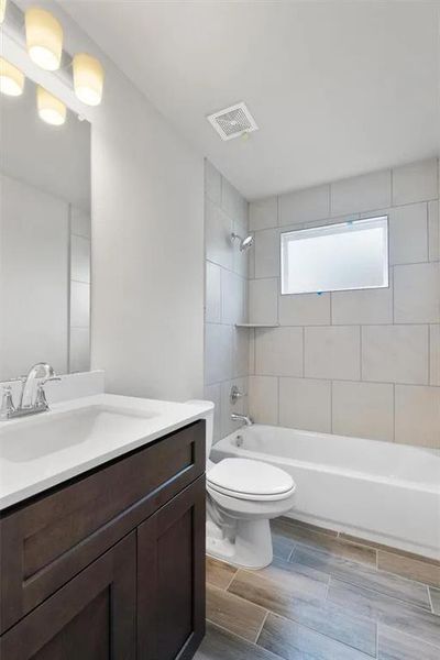 A well-appointed bathroom features a dark wood vanity and a tiled bath/shower combination.