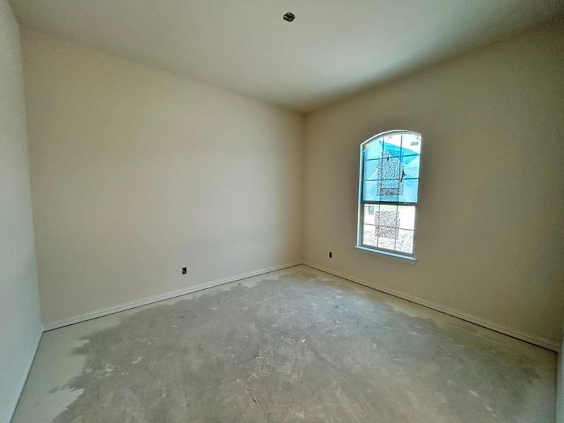 Spare room featuring unfinished concrete flooring and baseboards