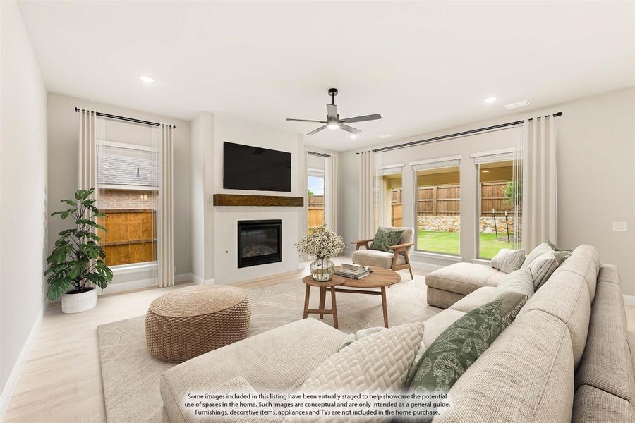 Living room with fireplace, ceiling fan, large windows, and light wood floors overlooking backyard Living room with fireplace, ceiling fan, large windows, and light wood floors overlooking backyard