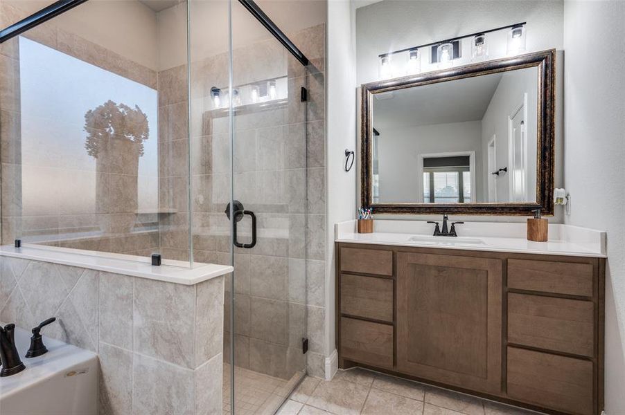 Full bath featuring a stall shower, vanity, a garden tub, and tile patterned floors Full bath featuring a stall shower, vanity, a garden tub, and tile patterned floors