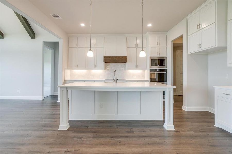 Kitchen with white cabinets, an island with sink, stainless steel appliances, and dark hardwood / wood-style flooring