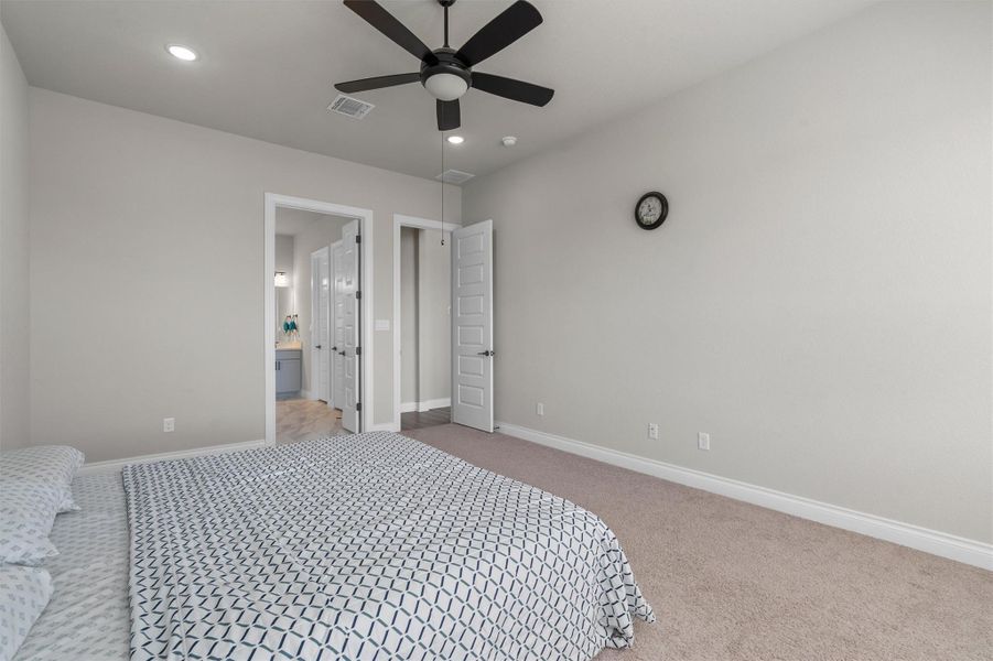Recessed lighting and soft carpeting create a serene and comfortable atmosphere in this bedroom.