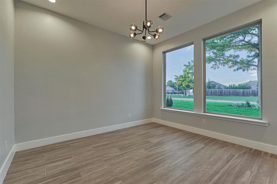 Another view of the office with large picture windows and wood plank vinyl flooring.