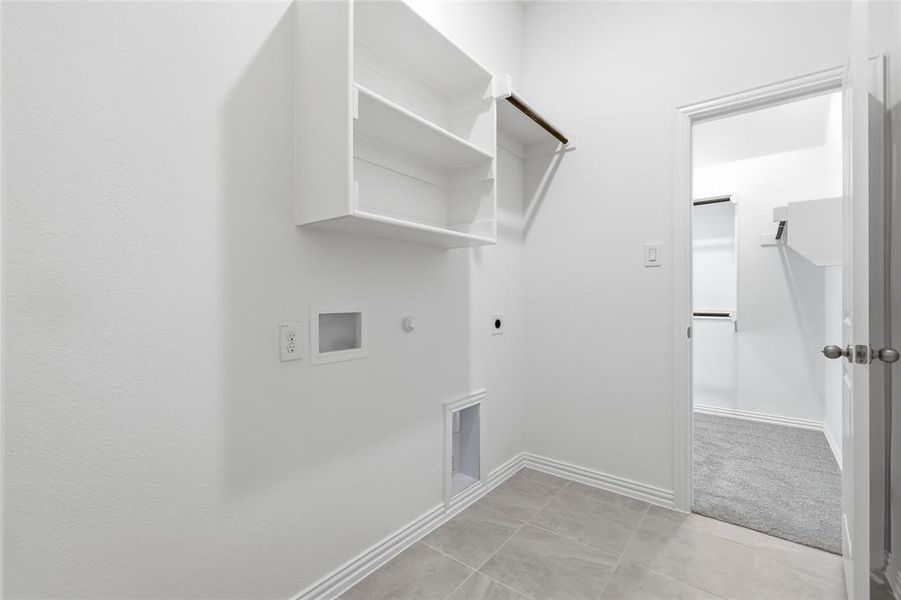 Laundry area featuring built-in shelving, a clothes hanging rod, and tile flooring