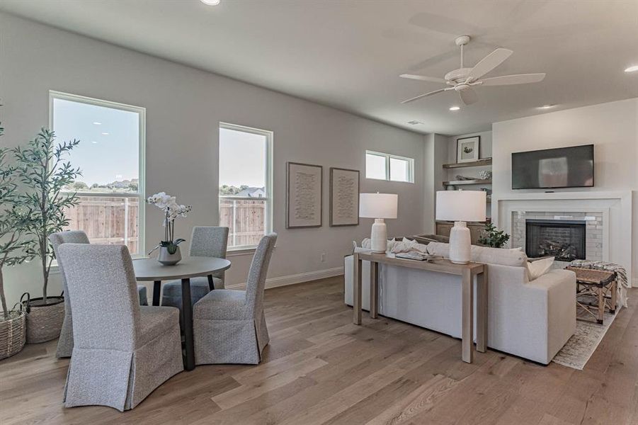 Living room with a brick fireplace, ceiling fan, and hardwood / wood-style flooring