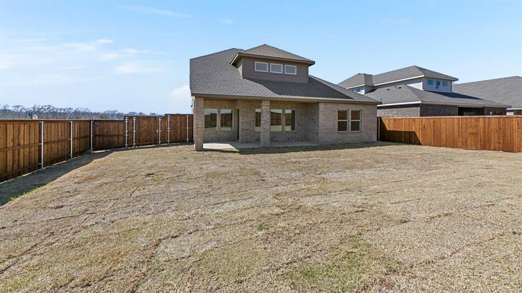 Rear view of property featuring a patio, brick siding, a fenced backyard, and a shingled roof