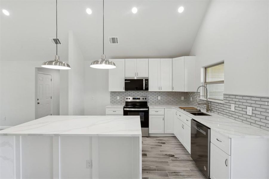 Kitchen with a center island, sink, decorative light fixtures, white cabinetry, and stainless steel appliances