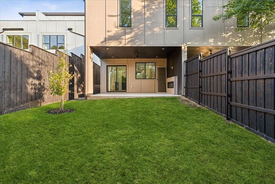 Rear view of house with ceiling fan, a lawn, and a patio