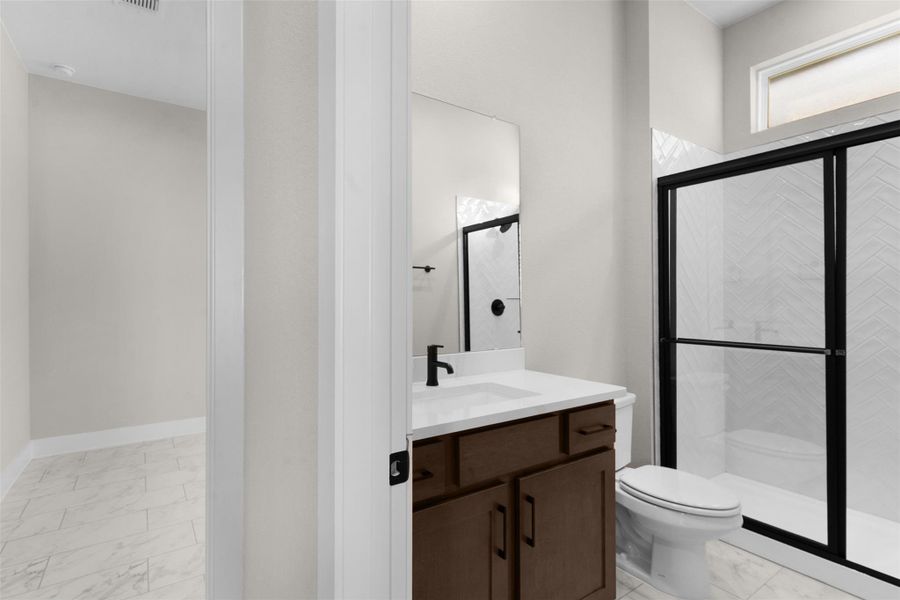 Full bathroom featuring a stall shower, light marble finish floors, and vanity