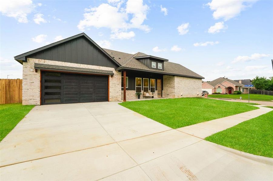 Modern home exterior featuring light brick, dark vertical siding, and a contrasting dark garage door with horizontal glass panels