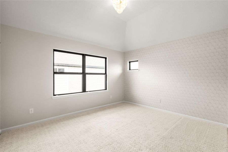 Bright and spacious bedroom with soft carpet, neutral tones, and ample natural light from large windows.