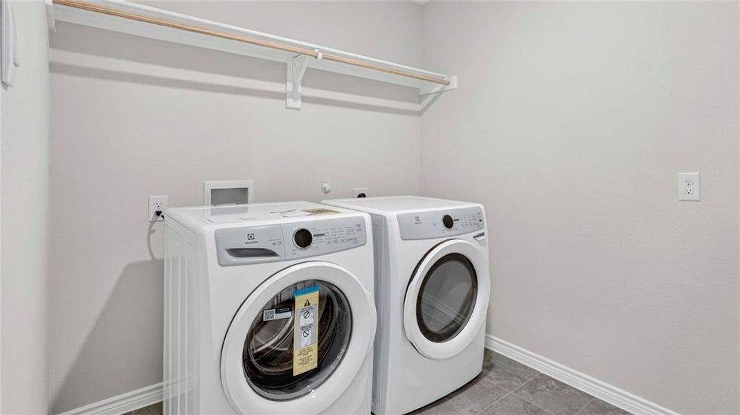 Dedicated laundry area featuring a light gray paint scheme and dark gray tile flooring