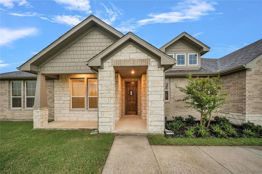 View of front facade featuring a front lawn, roof with shingles, stone siding, and brick siding View of front facade featuring a front lawn, roof with shingles, stone siding, and brick siding