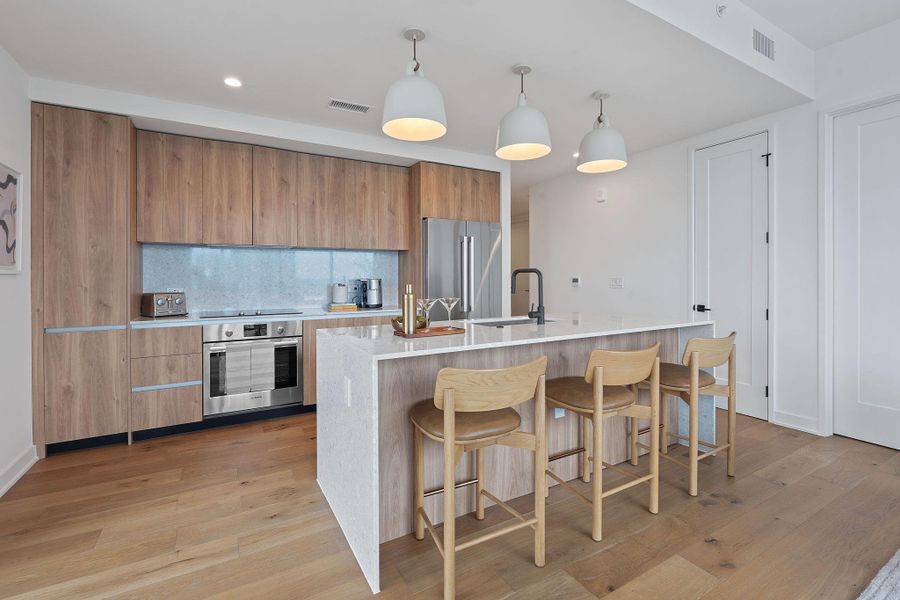 Representative Photo. Kitchen featuring custom Italkraft cabninetry, terrazzo backsplash, waterfall-edge terrazzo countertops, stainless steel Bosch appliances, and pendant lighting above kitchen island