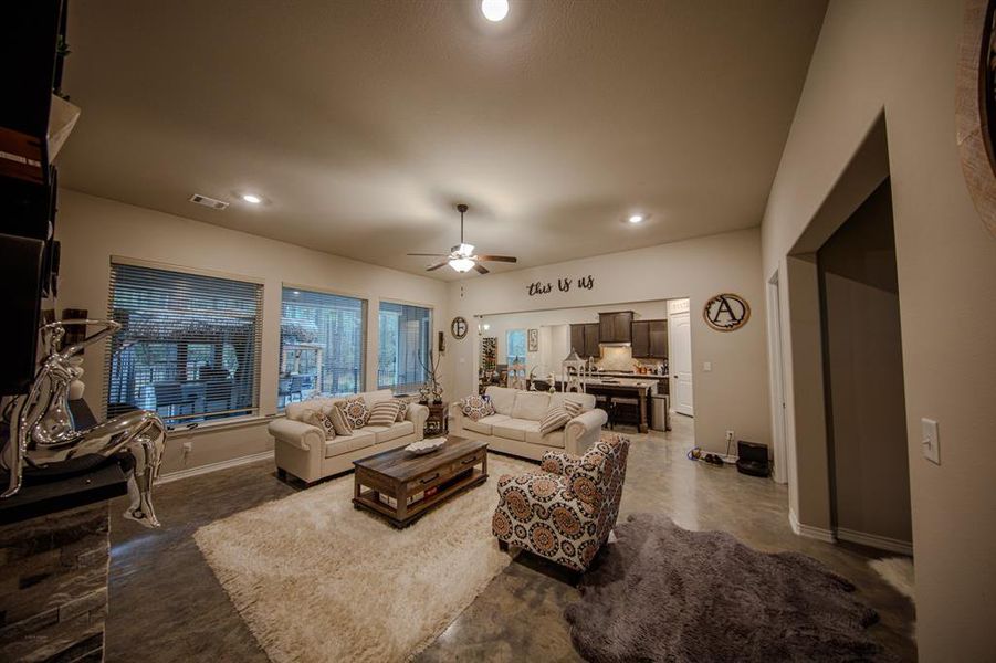 This photo showcases a spacious, open-concept living area with neutral tones and modern decor. It features a comfortable seating arrangement, large windows for natural light, and connects seamlessly to the kitchen. The space feels inviting and well-lit, perfect for family gatherings.