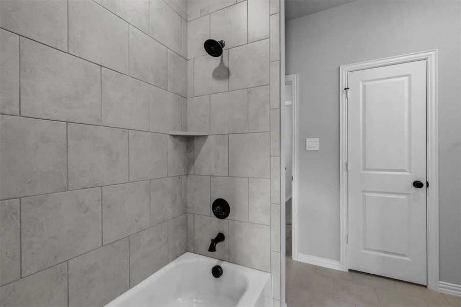 Bathroom featuring tiled shower / bath combo and tile patterned floors