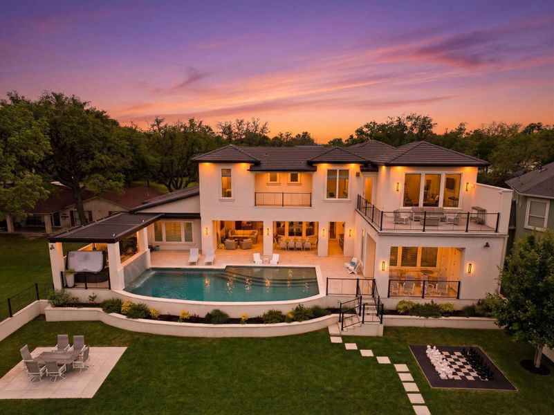 Back of house at dusk with a patio, outdoor lounge area, a balcony, a fenced backyard, and stucco siding