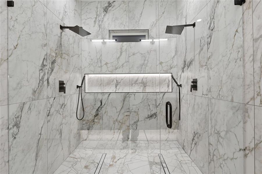Spacious walk-in shower featuring marble-look wall and floor tiling