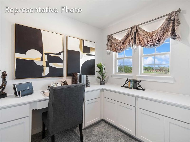 Carpeted home office featuring built in desk