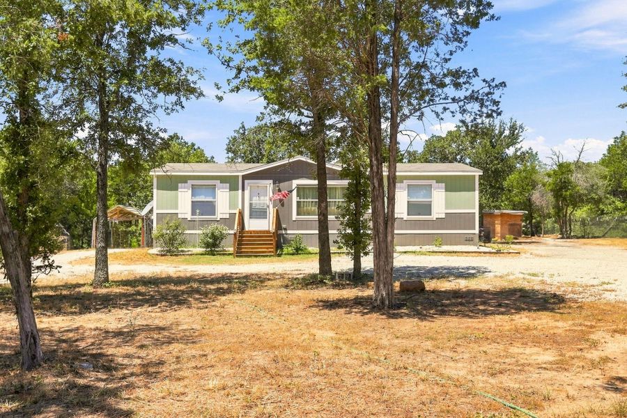 Mature trees frame a charming home nestled in a quiet, wooded setting.