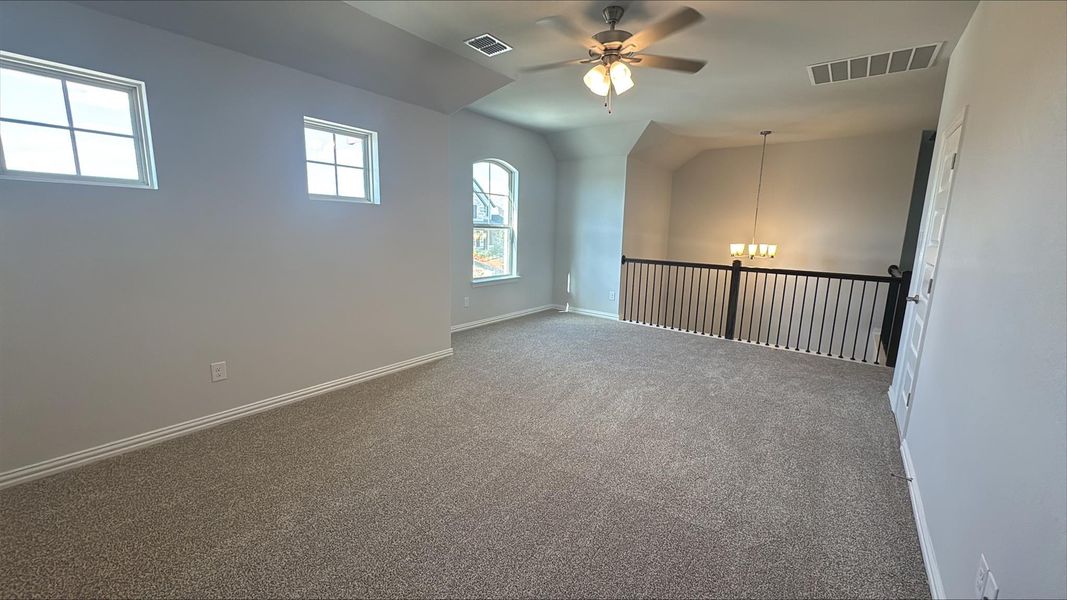 Spare room with carpet floors, ceiling fan, lofted ceiling, and a chandelier Spare room with carpet floors, ceiling fan, lofted ceiling, and a chandelier