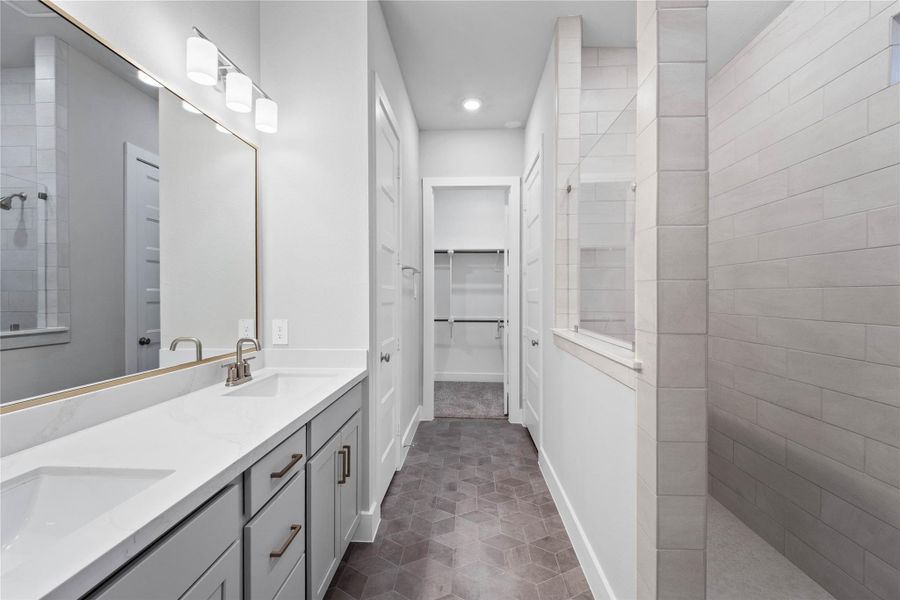 This stunningly updated primary bathroom is truly move-in ready! It features stained cabinetry with light countertops, dual vanities, a large framed mirror, high ceilings, custom paint, tile flooring, and sleek modern finishes throughout.