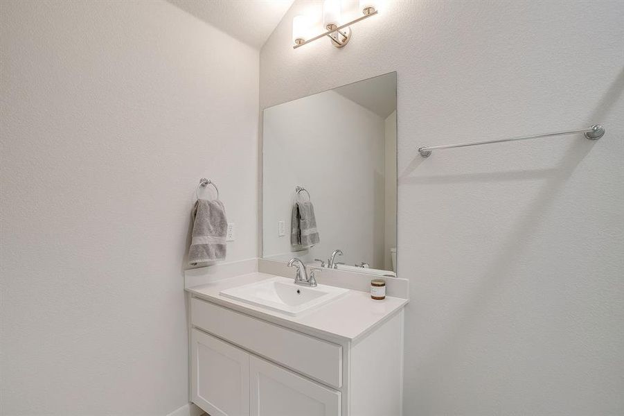 Bathroom featuring vanity and a textured wall Bathroom featuring vanity and a textured wall