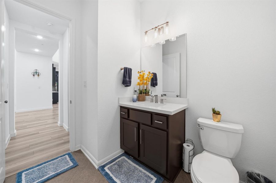 The bathroom features a vanity with a white countertop and a mirror with overhead lighting