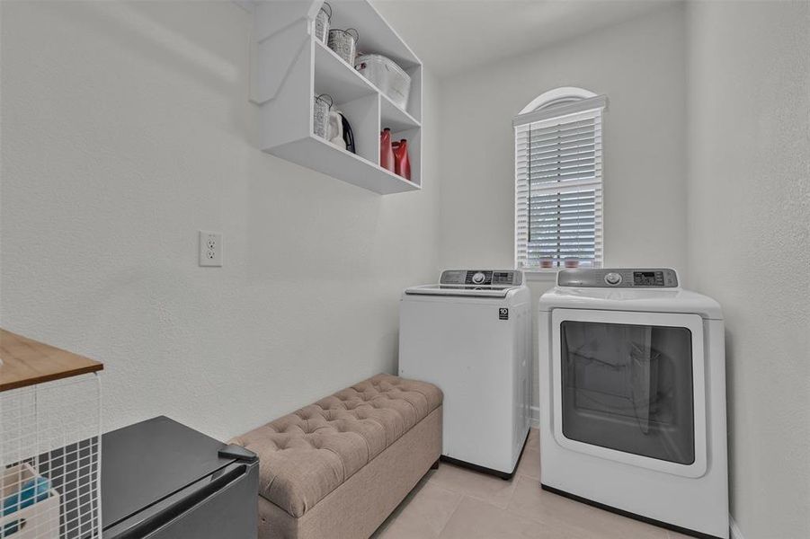 Laundry room featuring a top-load washer, front-load dryer, and an arched window with blinds Laundry room featuring a top-load washer, front-load dryer, and an arched window with blinds