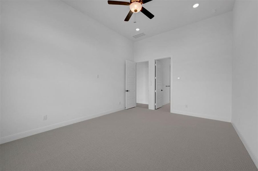 Empty room featuring carpet floors, a high ceiling, ceiling fan, and recessed lighting