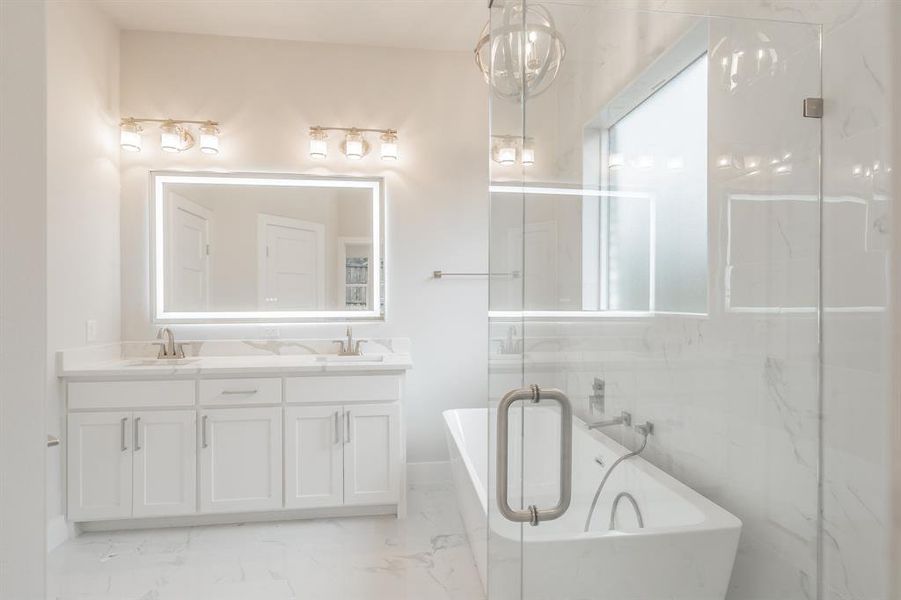 Full bath with a freestanding bath, double vanity, light marble finish floors, and a marble finish shower