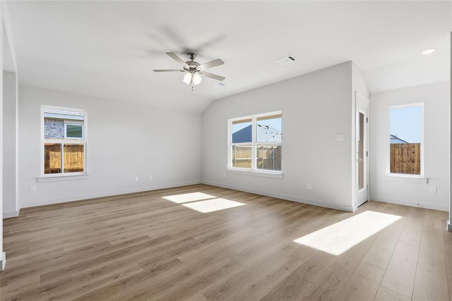 Empty room featuring lofted ceiling, ceiling fan, and light wood-style floors