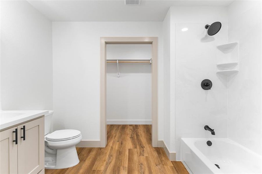 Full bath with a walk in closet, vanity, light wood finished floors, and bathtub / shower combination Full bath with a walk in closet, vanity, light wood finished floors, and bathtub / shower combination