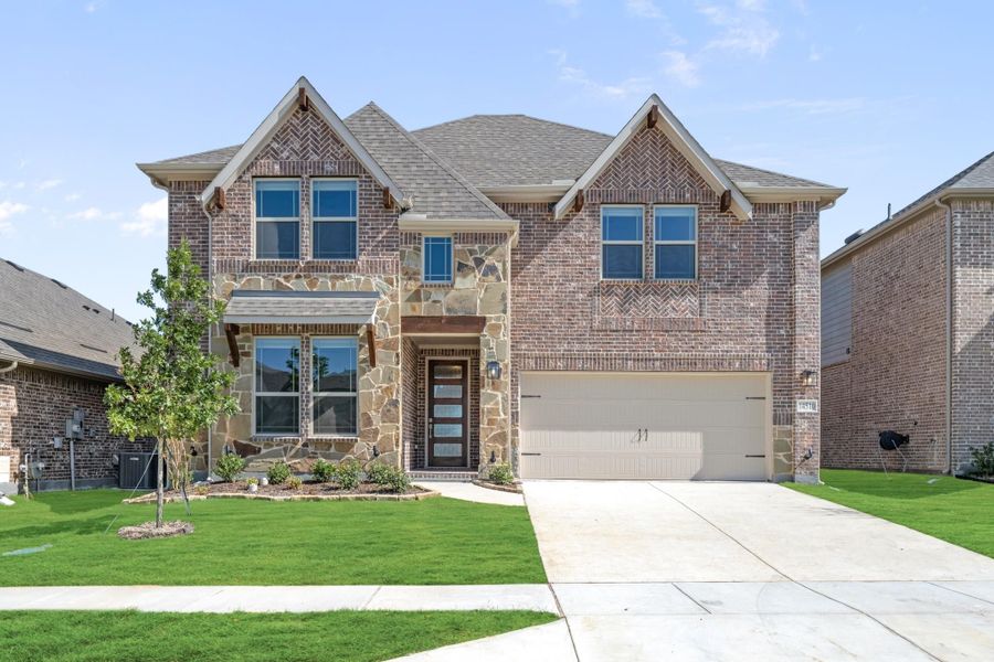Two-story brick and stone home with two-car garage and green front lawn Two-story brick and stone home with two-car garage and green front lawn