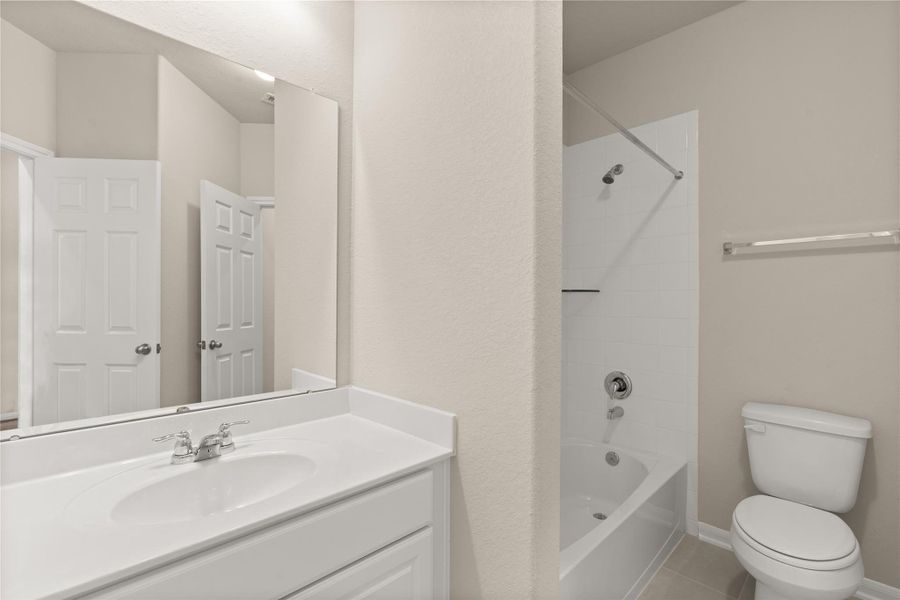 The secondary bath features tile flooring, white cabinetry and light countertops with a shower-tub combo. Perfect for accommodating any visiting family and friends.