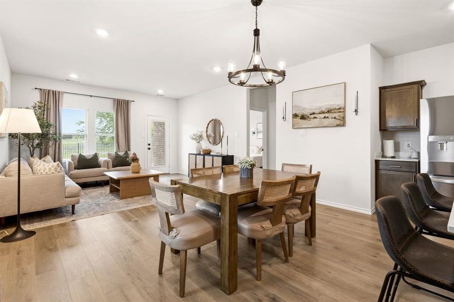 Open concept living and dining area featuring light-toned flooring, a modern chandelier, and recessed lighting Open concept living and dining area featuring light-toned flooring, a modern chandelier, and recessed lighting