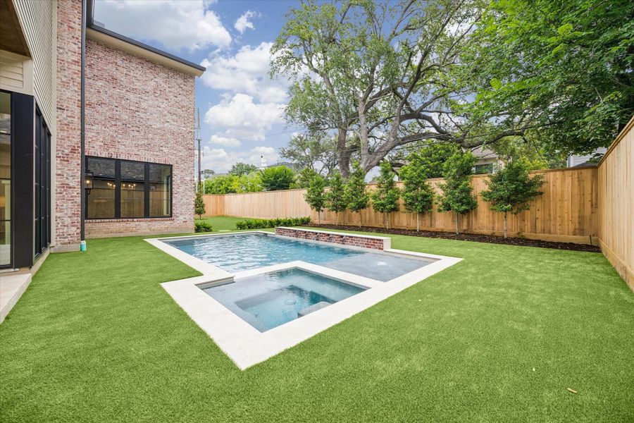 Beautiful pool and hot tub surrounded by artificial turf.